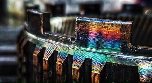 Iridescent rainbow light reflecting on metallic computer hardware components with ribbed heat sink fins